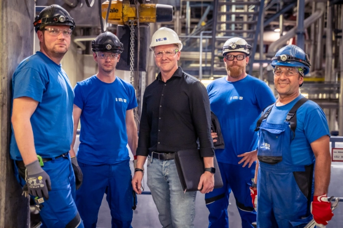 5 Personen des IMB-Teams stehen in einer Betriebshalle